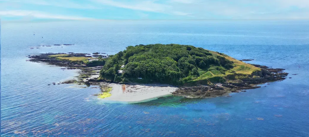 Aerial view of St. George's Island surrounded by water, featuring greenery and rocky shoreline.